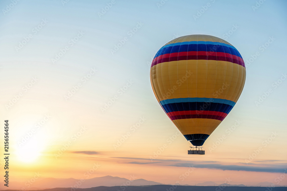 Fototapeta premium Colorful hot air balloon soaring above mountain silhouettes at s