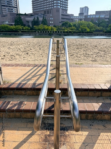 Cuadro en lienzo 砂浜と水辺へ続く階段、金属製手すりがある都市景観｜階段,手すり,砂浜,水辺,ビル