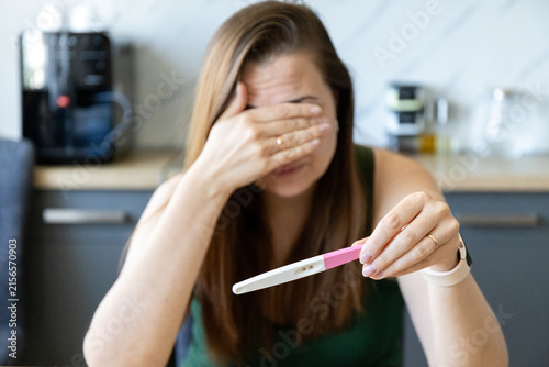 Foto Unhappy young woman with a positive pregnancy test in her hand at home