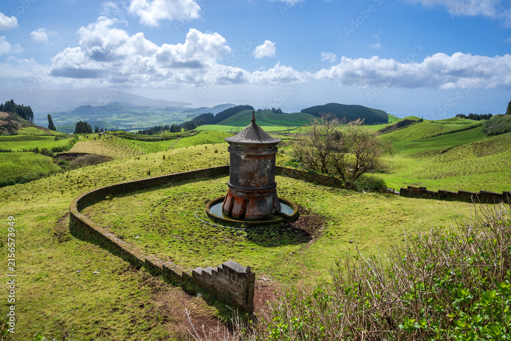 Fototapeta premium Traditional stone water fountain on green rolling hills in Sao Miguel Island Azores Portugal