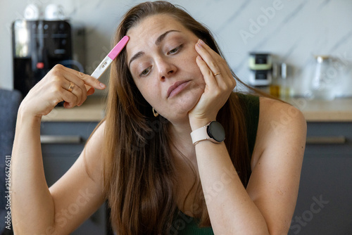 фотографія Thoughtful young woman with a positive pregnancy test at home