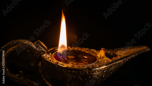 Ancient metallic oil lamp with a bright flickering flame in dark atmosphere mysterious traditional decoration oriental spiritual meditation stillness lighting cultural craftsmanship