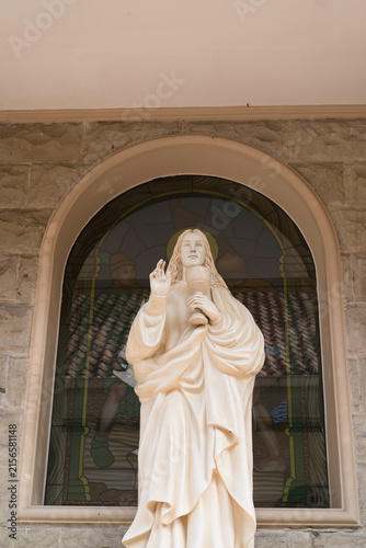 Foto A serene statue of a religious figure stands in an arched window, surrounded by stone
