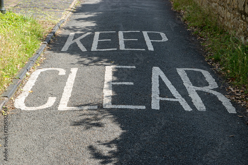 Keep Clear road marking painted on a narrow residential street in England.