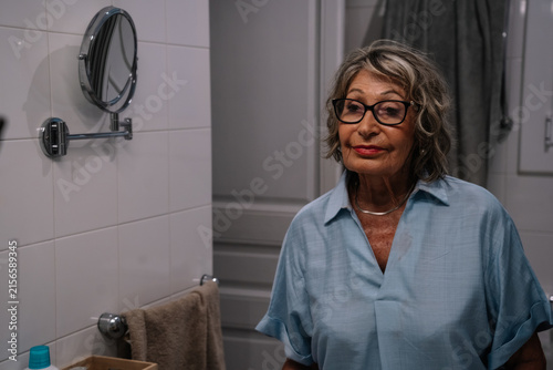 Senior woman looking at reflection in magnifying mirror