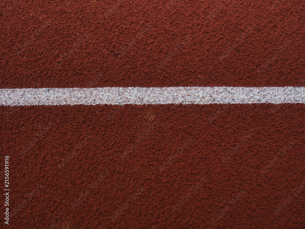 Fototapeta premium Red synthetic rubber running track surface marked with crisp white lane lines.