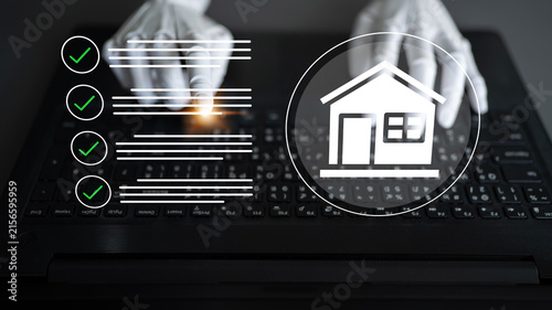 Obraz na płótnie A close-up shot of hands in protective gloves typing on a laptop keyboard, featuring check marks and a house icon, symbolizing modern real estate tasks and safety