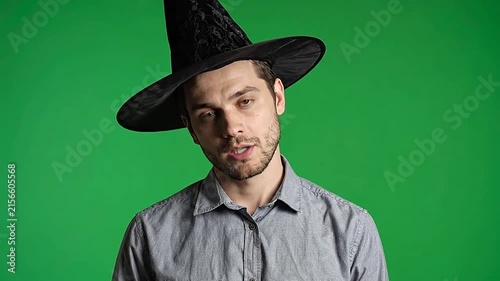 A young man wearing a black pointed hat against green background
