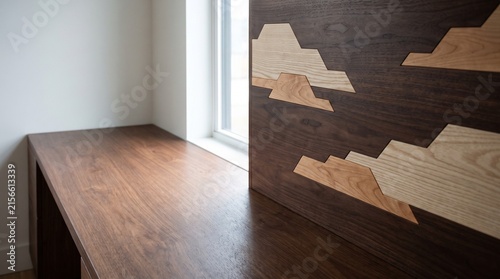 Minimalist high angle shot of a wooden intarsia artwork showcasing geometric cloud shapes next to walnut desk copy space. Generative AI