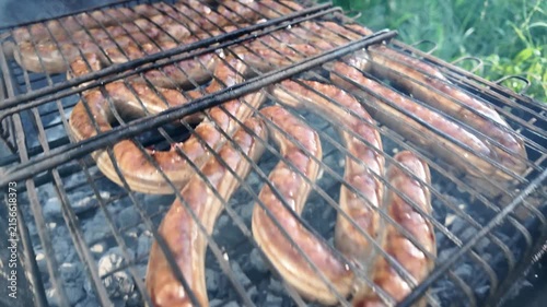 Meat sausages are fried in the grill grate. Cooking barbecue food on the grill with smoke.