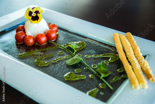 Food Photography art shots, white Cheese surrounded by charry tomatoes with watercress and green sauce making a flower shape, Caprese, Photo is selective focus with shallow depth of field. Cairo Egypt