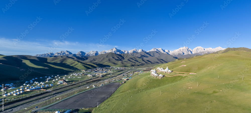 Naklejka premium Panoramic View of Maya Snow Mountain with Grassland and Tibetan Tent Camps at Morning