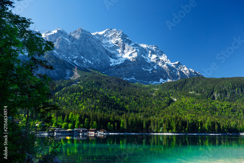 Travel landscape of Zugspitze Alps in Bavaria, Germany, scenic summer nature panorama with forest, Eibsee lake, snow mountains peak. Alpine landscape