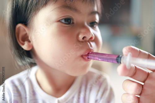 Child taking syrup medicine from an oral syringe, Sick and Feverish Children, Pediatric healthcare, Medical treatment, Child care, and medication, Asian Thai Child