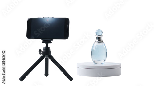 Smartphone on tripod filming perfume bottle, mobile product photography setup on white background, digital content creation for social media