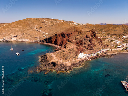 Quadro su tela Wide aerial drone shot of Red Beach bay with yachts and red volcanic headland in