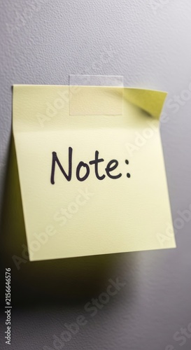 Yellow Sticky Note with Note - Text Adhered to a Surface.