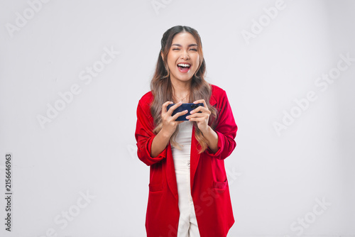 Beautiful young Asian woman in a red jacket is using smartphone playing online games.