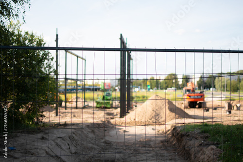 Obraz na plátne Temporary mesh fence surrounding a construction site with ongoing earthworks
