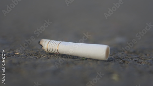 Foto Discarded Cigarette Butt on Asphalt, Smoking and Environmental Pollution Concept