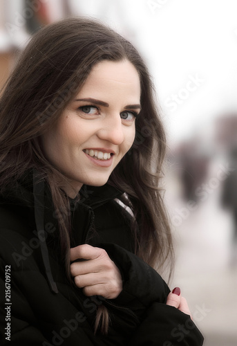 Foto Close-up portrait of a smiling young woman in a black winter jacket outdoors