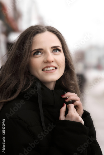 Foto Close-up portrait of a smiling young woman in a black winter jacket outdoors