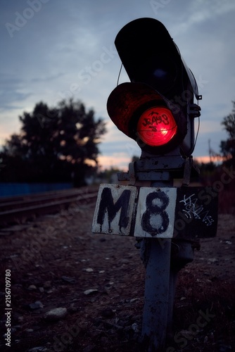 Moody railway signal with red light at dusk