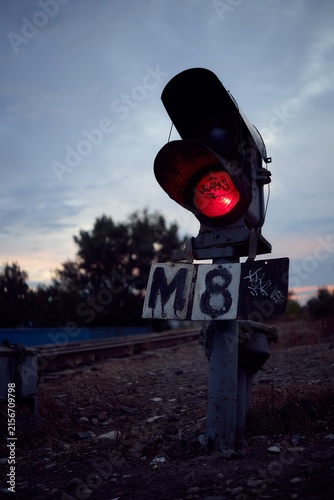 Moody railway signal with red light at dusk