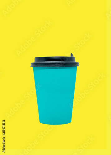 Teal disposable coffee cup with black lid isolated on yellow background. Blank mockup template for creative design and branding projects. Minimalist product photography concept.