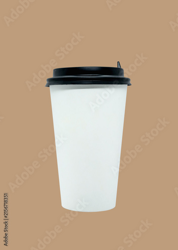 White disposable coffee cup with black lid isolated on beige background. Blank mockup template for creative design and branding projects.