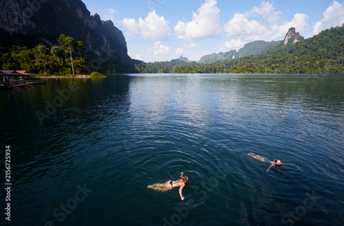 Bild auf Leinwand Tranquil Lake Scene With Swimmers and Lush Mountain Scenery