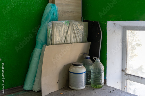 Obraz na plátně Stacked plastic bottles and wrapped building materials lean against a vibrant gr