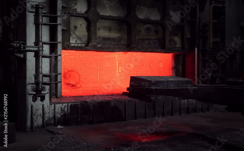 Bild auf Leinwand A large open furnace reveals a glowing red-hot interior, with thick metal walls and a mechanical arm positioned nearby, emphasizing high-temperature metal treatment and precision forging operations