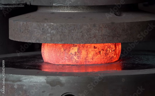 Cuadro en lienzo Industrial hydraulic press applying heavy pressure to shape a glowing hot metal