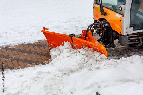 Snow removal at a city street during winter with a snowplow clearing the path