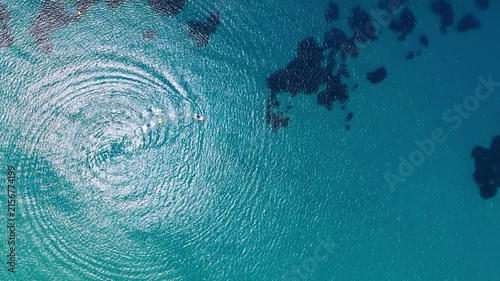 Circular boat wake spreading across turquoise Greek sea