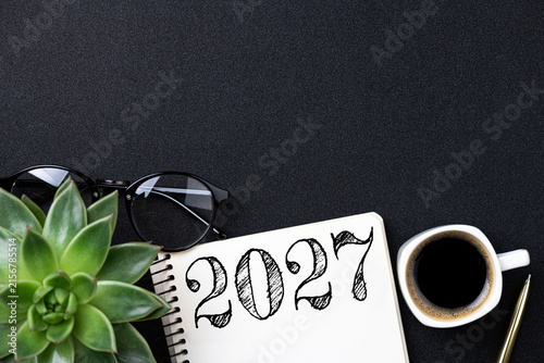 New year resolutions 2027 on desk. 2027 goals list with notebook, coffee cup, plant on black table. Resolutions, plan, goals, action, checklist, idea concept. New Year 2027 resolutions, copy space