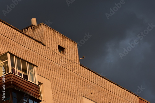 Detail of the facade of a modern apartment building with dark clouds