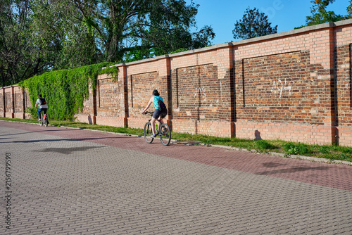 people riding bicycles near a brick wall