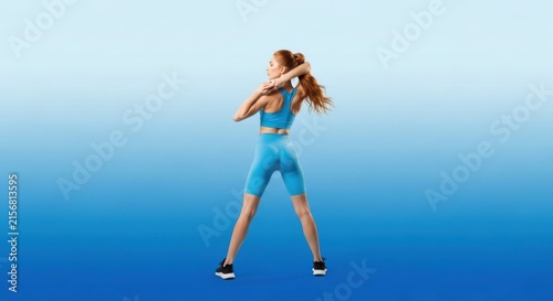 Athletic Woman Stretching in Bright Blue Sportswear on Gradient Blue Studio