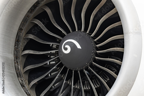 Close up view of commercial airplane jet engine turbine fan blades with white spiral on the black spinner hub cowl cover