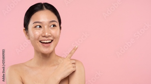 Smiling Asian Woman Pointing Finger at Copy Space