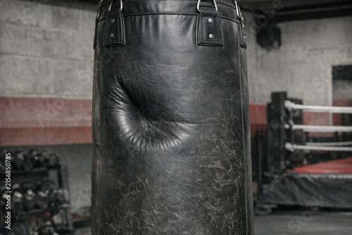 A punching bag hanging from the ceiling of a boxing ring, ready for a workout