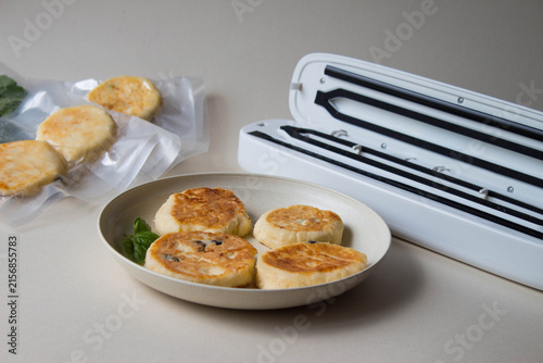 Homemade cottage cheese pancakes prepared for vacuum sealing. Some vacuum packagings of ready-made fried pancakes. Sealing machine for vacuum sealing food, freezer storage, freshness extension