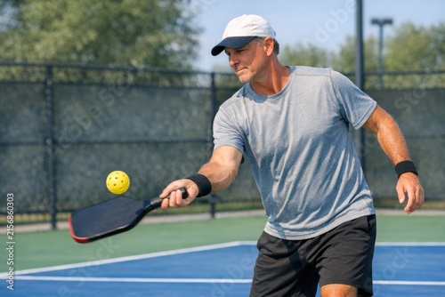 A person hits a tennis ball with a tennis racket, likely in the midst of a match or practice