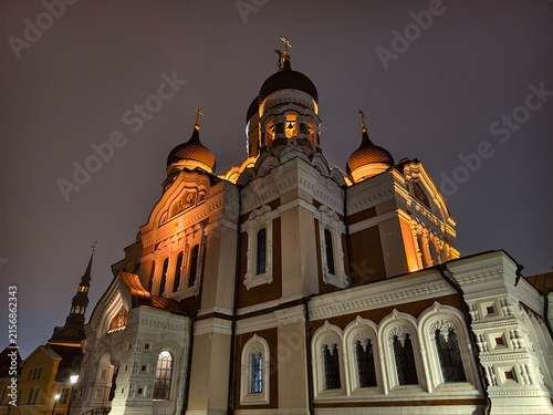 Low angle wide view of illuminated facade and onion domes of Alexander Nevsky Cathedral at night in Tallinn, Estonia