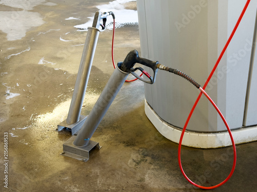 Highpressure water spray lances stored in metal holders at a self-service car wash bay