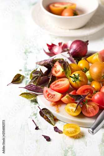 Fresh heirloom cherry tomatoes with purple basil on cutting board