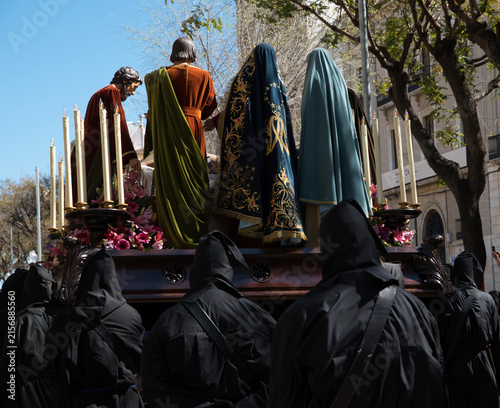 Bild auf Leinwand A Holy Week procession in Spain featuring a local religious brotherhood with hooded penitents and a float bearing religious images, which has been designated a site of international tourist interest