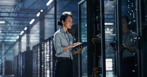 фотографія Asian Female System Administrator Working With Tablet Computer Beside Server Rac